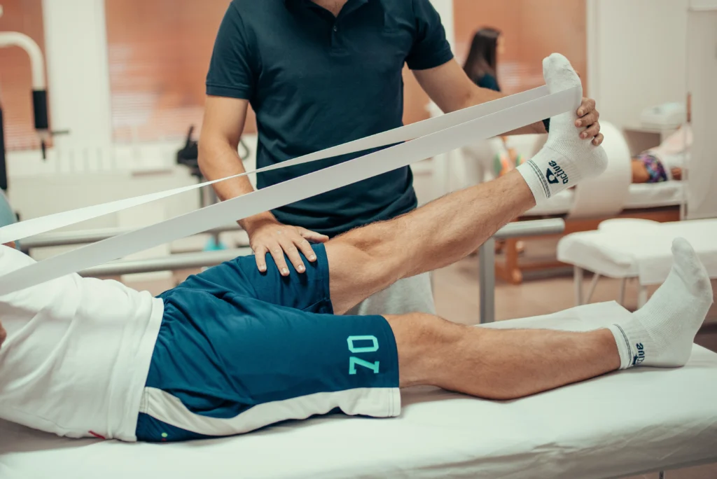 Physiotherapist assessing a patient's lower limb during rehabilitation.