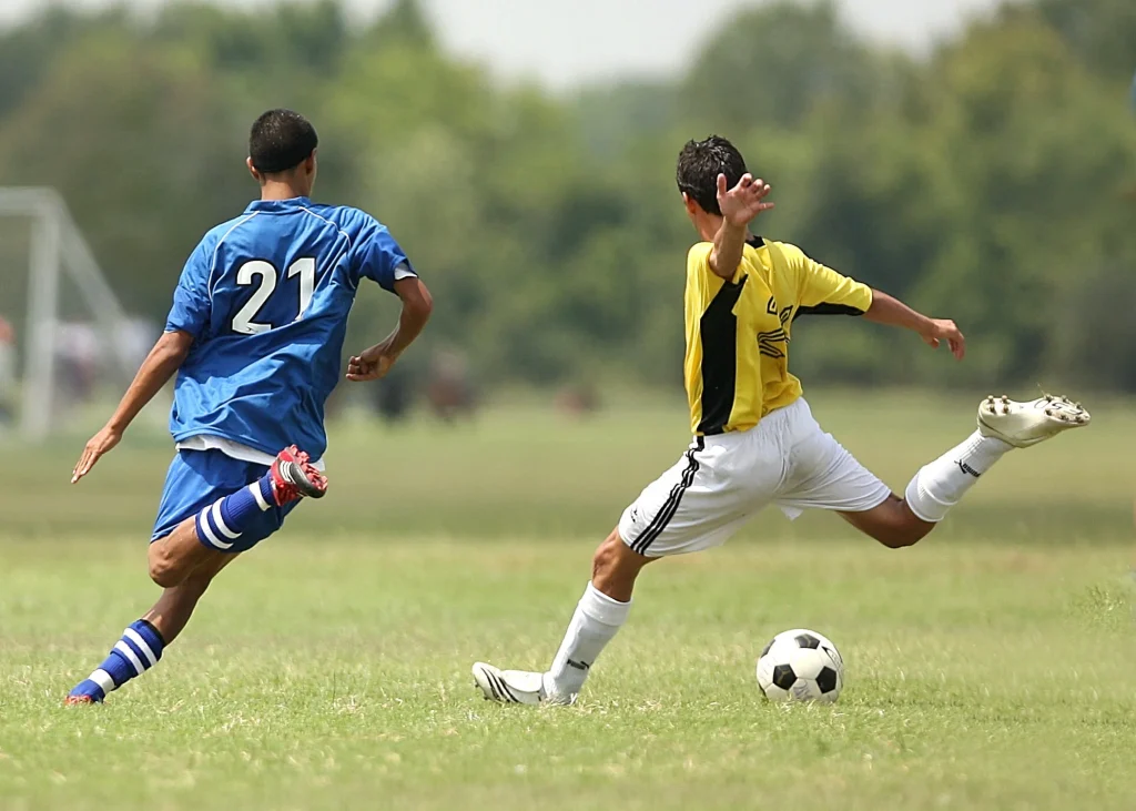 Young football player kicking a ball during sport